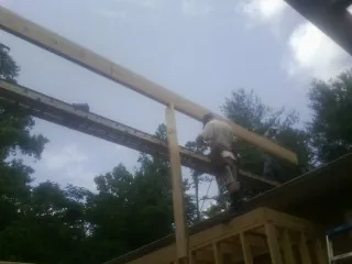 Carpenter setting a ridge beam over a new addition frame — Ice Dam Removal by Roofing Brothers in Bellevue